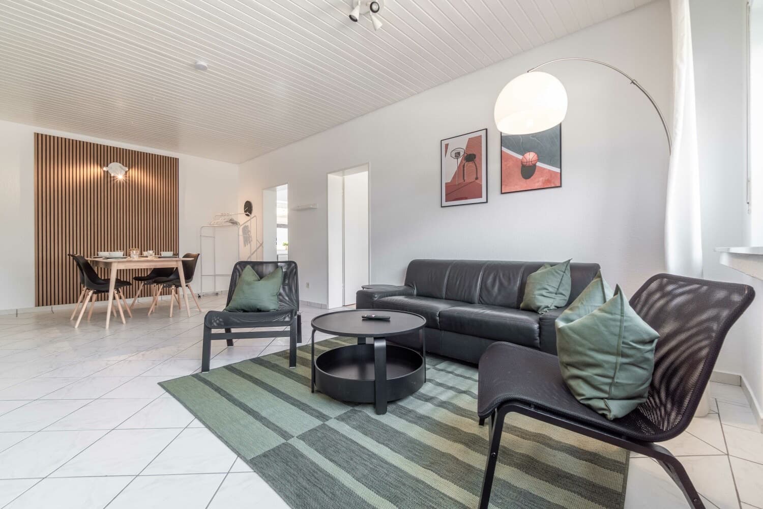 Wohnzimmer mit Ledersofa, Sesseln und Holzlamellenwand