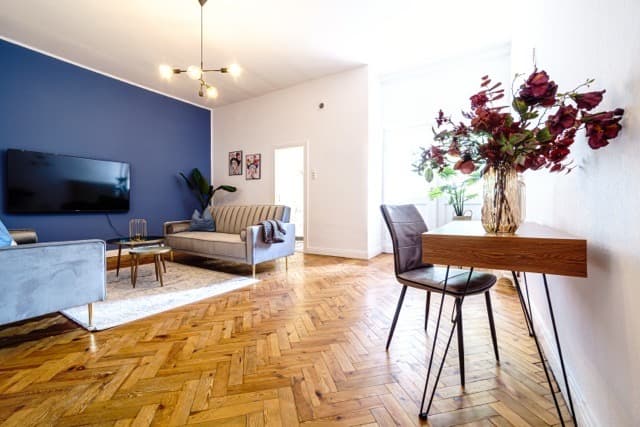 Wohnzimmer der Altbauwohnung S14 mit Sofa, Smart-TV und Arbeitsplatz