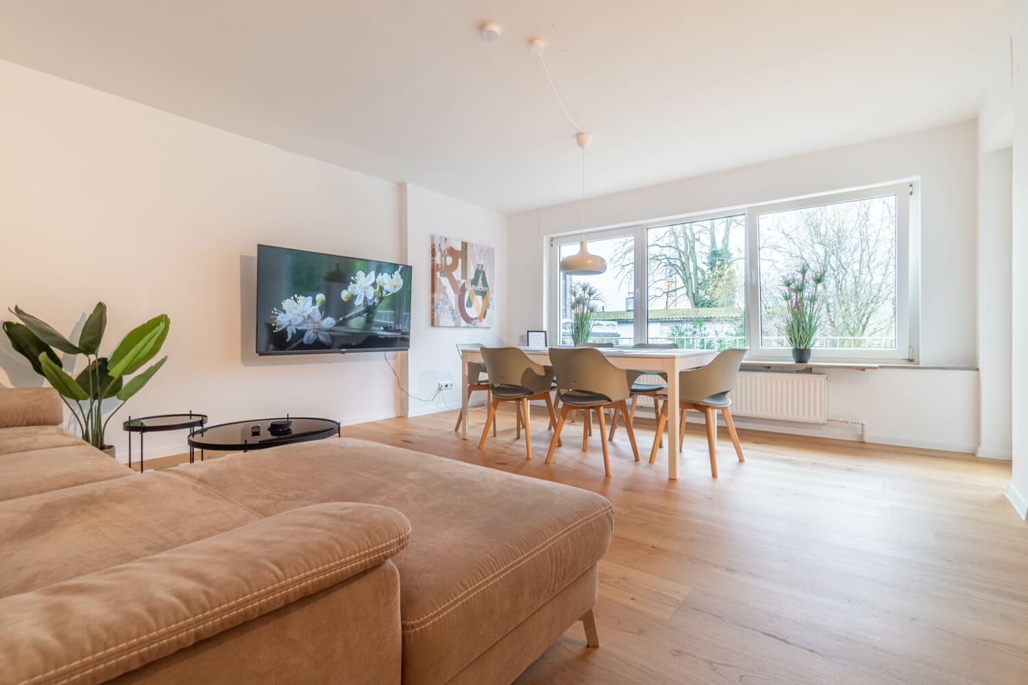 Helles Wohnzimmer mit Sofa und Essbereich in einer Wohnung von KAMA Rooms in Bocholt